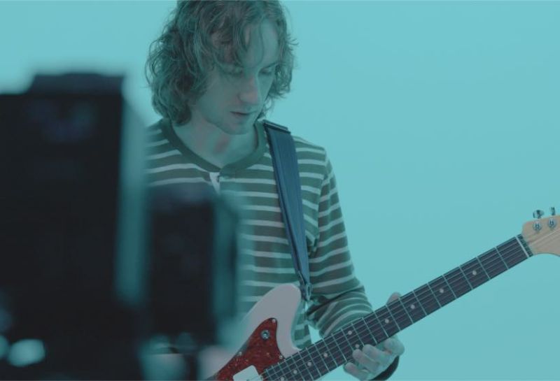 man playing guitar being recorded 