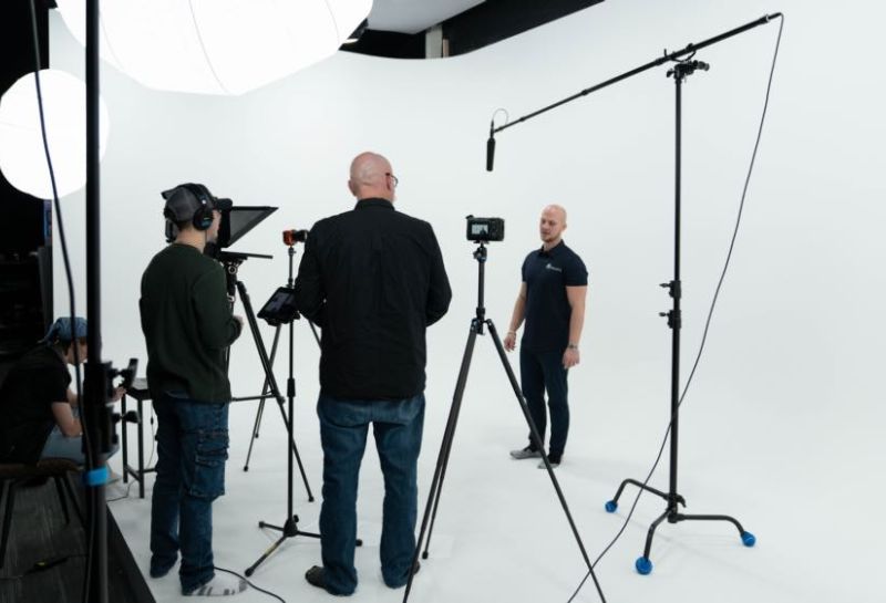person being recorded background is white walls and their lights and cameras 